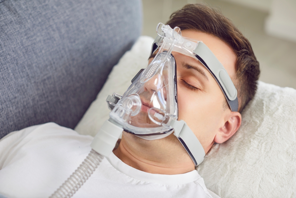 Portrait of a man sleeping at home, inhaling through an oxygen mask